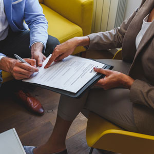 Two people signing documents, one possibly a trust protector, indicating a legal or trust agreement.