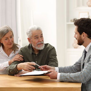 Elderly couple discussing paperwork with a Lawyer at a table representing elder law