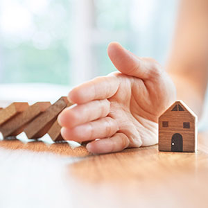 Estate planning for Florida business owners depicted with a hand protecting a wooden house