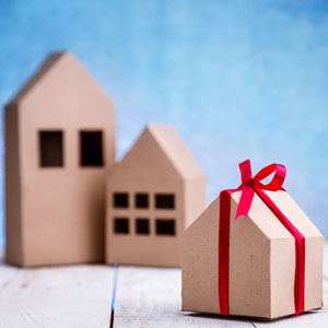 Cardboard house models and gift box with red ribbon, symbolizing asset gifting in Florida.